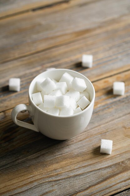 Tasse avec des morceaux de sucre sur une surface en bois libre