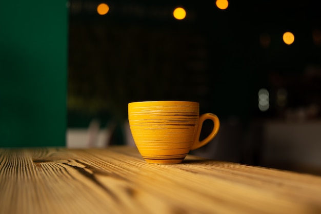 Tasse orange vif sur un fond sombre flou avec bokeh