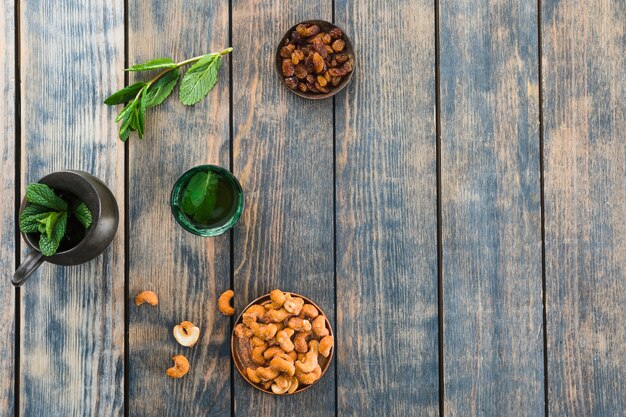 Tasse près du pichet avec des fruits secs, des plantes et des noix