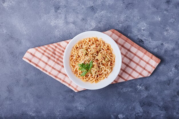 Une tasse de spaghettis à la sauce tomate sur un torchon.