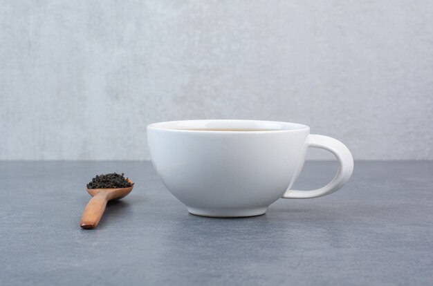 Une tasse de thé aromatique avec une cuillère en bois d'infusion.