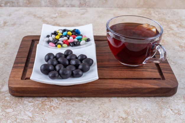 Tasse de thé et assiette de chocolats sur planche de bois