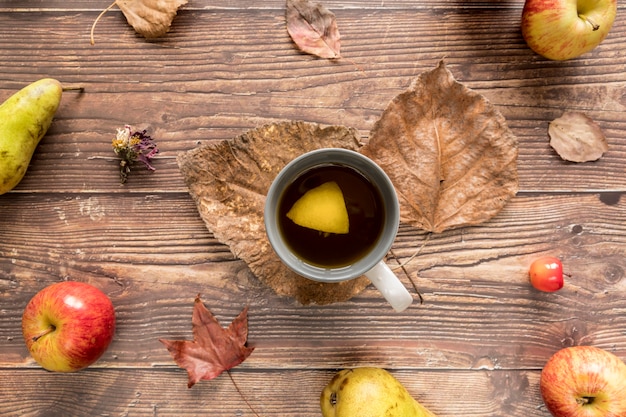 Tasse avec thé au citron parmi les fruits d'automne