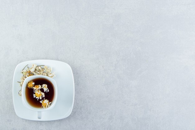 Tasse de thé aux fleurs de camomille séchées.