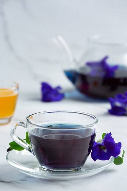 Tasse de thé aux fleurs de pois papillon avec du miel sur la table