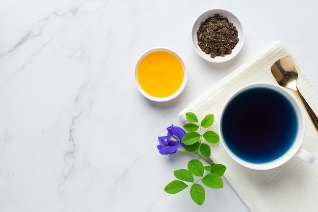 Photo gratuite tasse de thé aux fleurs de pois papillon avec du miel sur la table