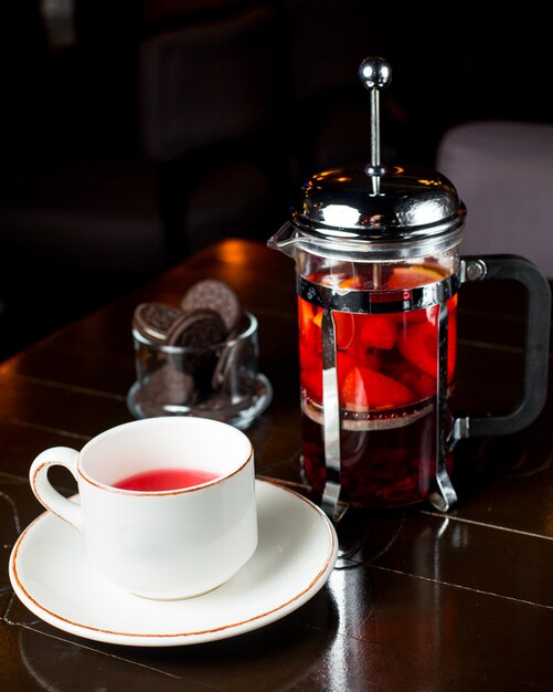 Tasse de thé aux fruits et presse française sur la table