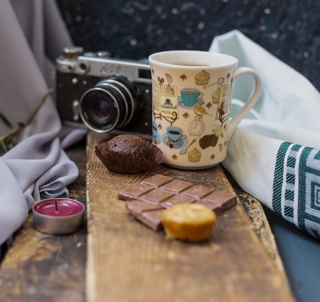 Une tasse de thé avec une barre de chocolat sur un morceau de bois.