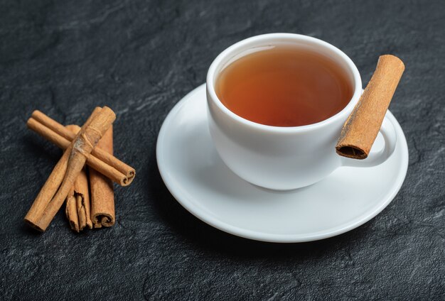 Une tasse de thé avec des bâtons de cannelle et une infusion.