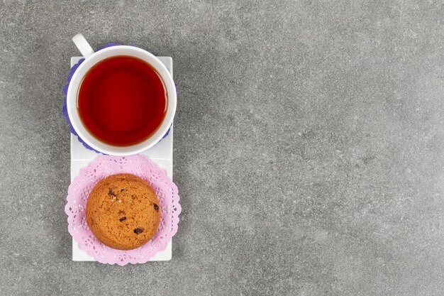 Tasse de thé et biscuits aux chips sur soucoupe blanche