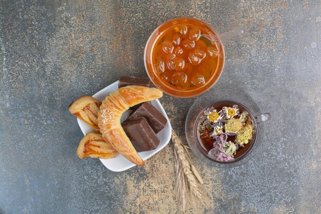 Tasse de thé, biscuits et confiture de baies sur une surface en marbre.