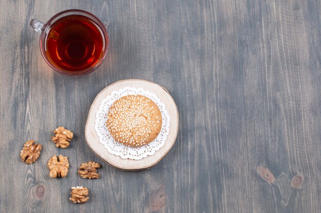 Tasse de thé, biscuits et noyaux de noix sur une surface en bois