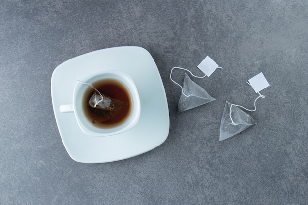 Une tasse de thé blanc chaud avec des sachets de thé.