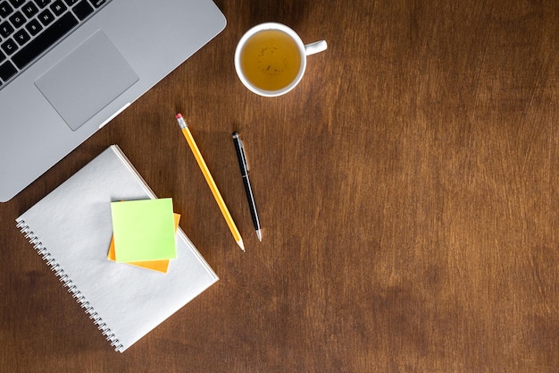 Une tasse de thé et un bloc-notes sur une table en bois