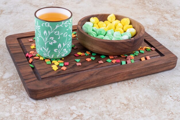 Tasse de thé et bonbons colorés sur planche de bois