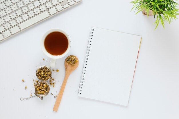 Tasse de thé avec cahier sur table blanche