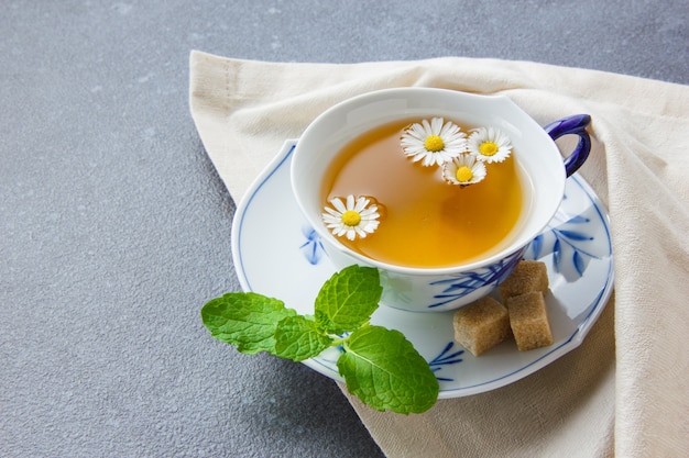 Une tasse de thé à la camomille avec des morceaux de sucre, laisse une vue grand angle sur un chiffon