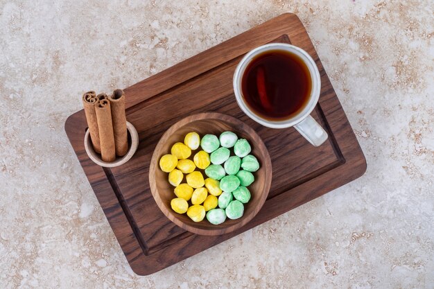 Tasse de thé, cannelle et bonbons sur planche de bois