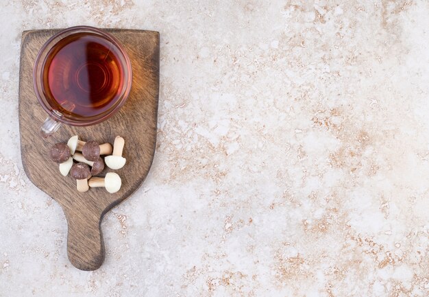 Une tasse de thé chaud avec des champignons sucrés sur une planche de bois