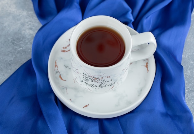 Tasse de thé chaud sur tissu bleu.