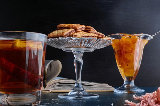 Une tasse de thé avec confiture de cerises et craquelins.