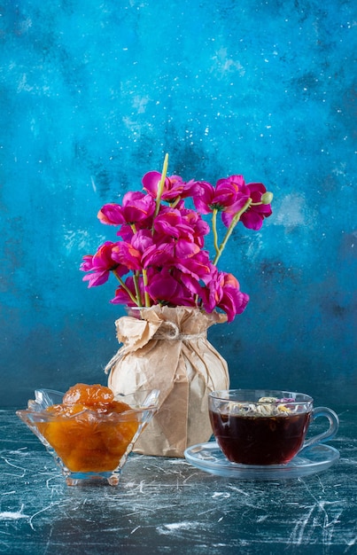 Une tasse de thé avec confiture de figues dans la soucoupe.