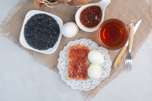 Photo gratuite tasse de thé avec du pain et des œufs sur un sac.