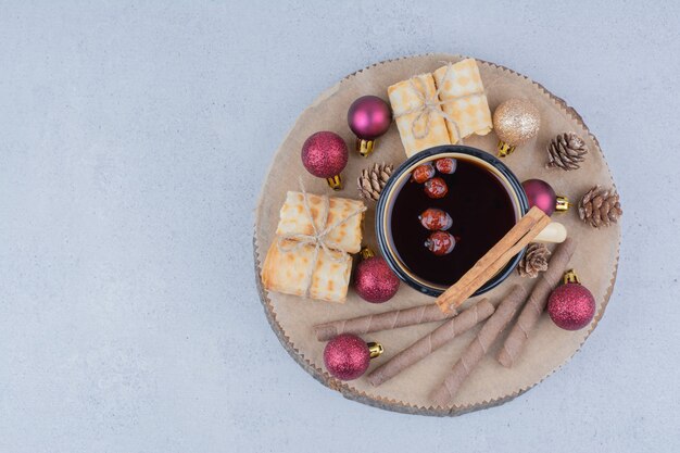 Tasse de thé à l'églantier, biscuits et boules sur planche de bois.