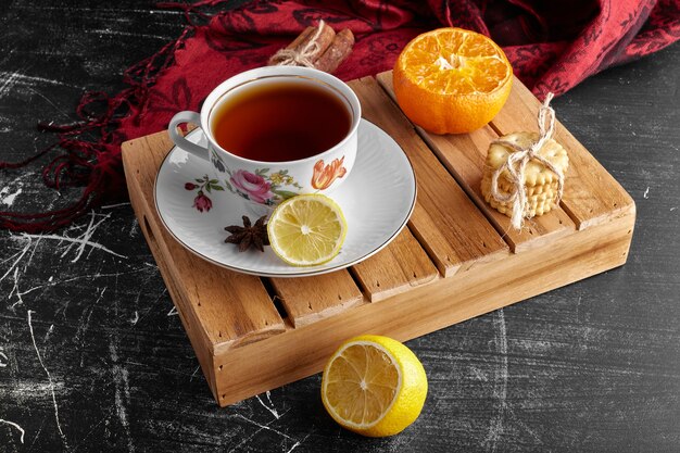 Une tasse de thé avec des fruits et des biscuits.