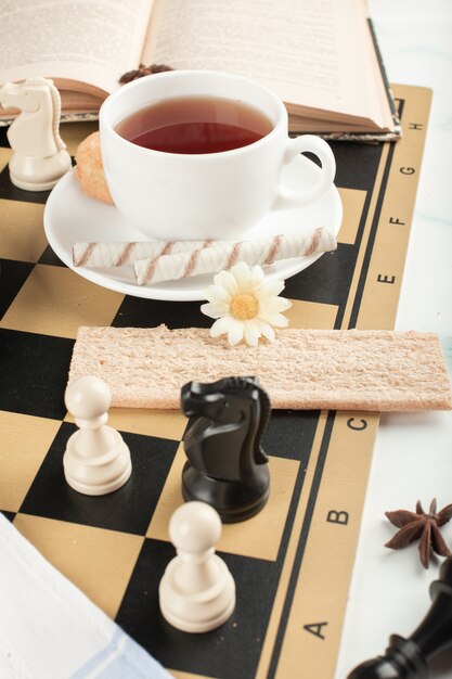 Une tasse de thé et une gaufre sur l'échiquier