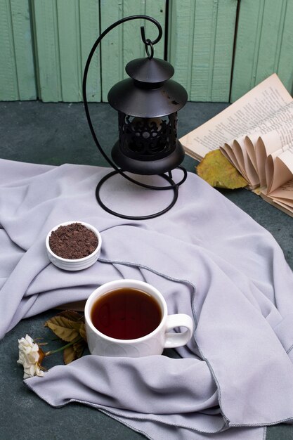 Une tasse de thé et d'herbes dans une soucoupe sur la table, un livre autour