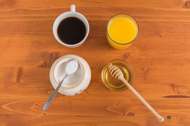 Tasse à thé; lait en poudre; jus d'orange et miel sur un bureau en bois