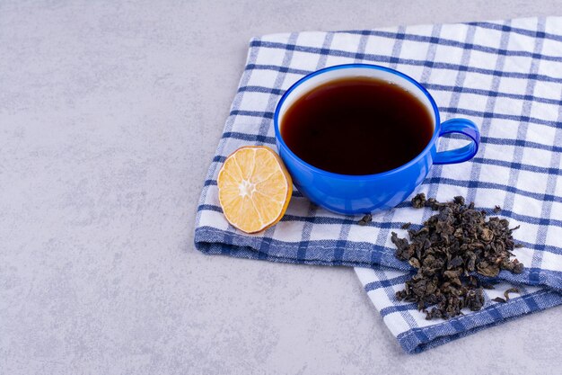 Tasse de thé sur nappe avec tranche de citron et thé sec. photo de haute qualité