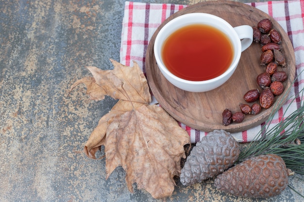 Tasse De Thé Noir Et D'églantier Séché Sur Plaque En Bois Avec Des Pommes De Pin. Photo De Haute Qualité