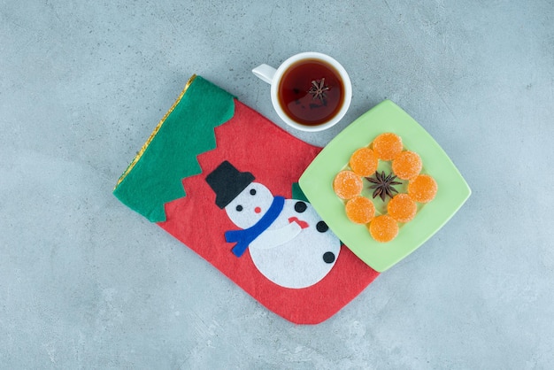 Tasse à thé et plateau de marmelade sur une chaussette de Noël sur marbre.