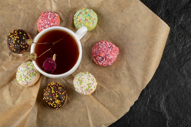 Une tasse de thé avec de la rose séchée et des beignets.