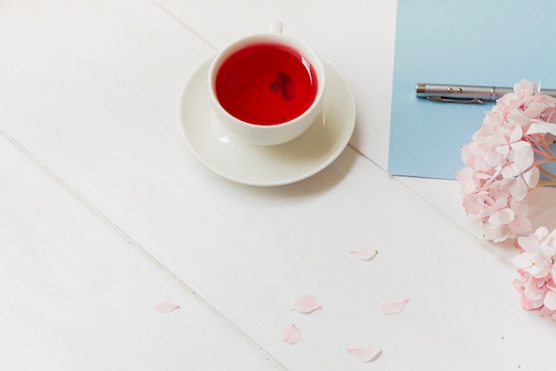 Tasse de thé rouge à côté de la fleur