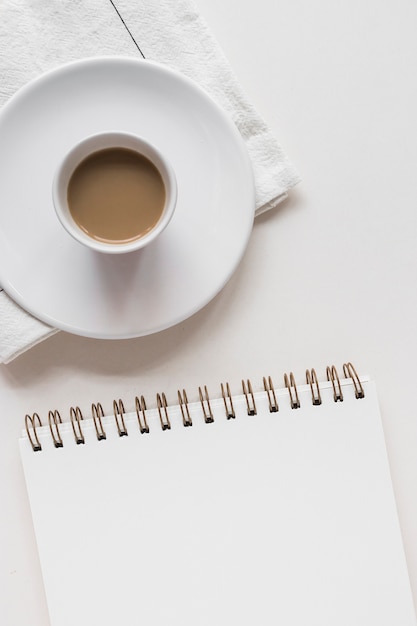 Tasse à Thé Et Soucoupe Sur Serviette Avec Bloc-notes En Spirale Sur Fond Blanc