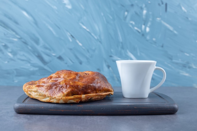 Une tasse de thé et de tarte sucrée sur un plateau en bois sur une table en marbre.