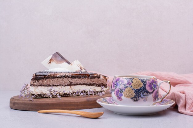 Une tasse de thé avec une tranche de gâteau au chocolat sur une surface grise