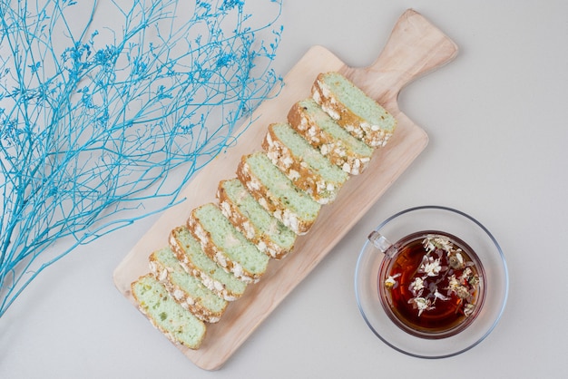 Tasse de thé et de tranches de gâteau sur blanc avec plante bleue.