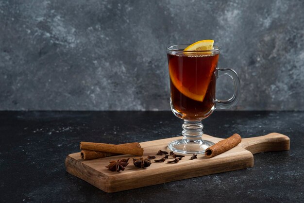 Une tasse de thé en verre et avec des bâtons de cannelle et des anis étoilés.