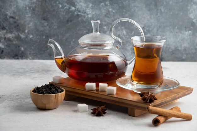 Une tasse de thé en verre avec du sucre et de l'anis étoilé.