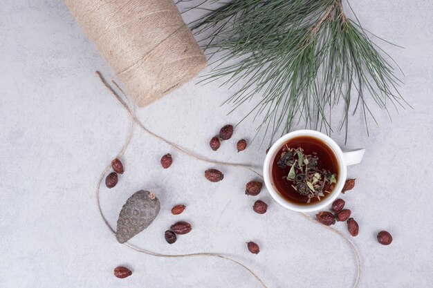 Tasse de tisane, canneberges séchées et pomme de pin sur table en marbre. Photo de haute qualité