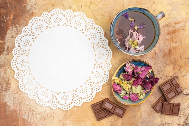 Photo gratuite une tasse de tisane chaude de fleurs de barres de chocolat et de serviette sur une tisane de couleur mixte