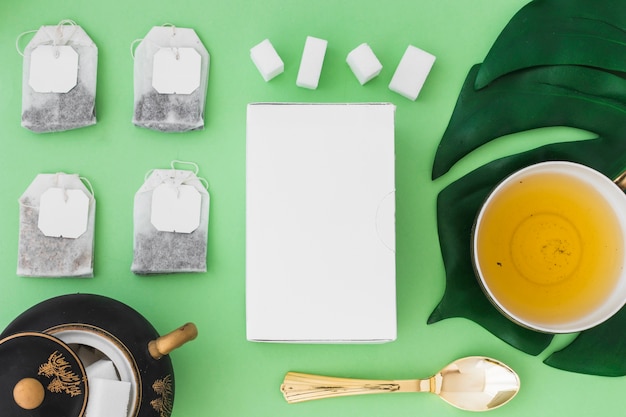 Tasse de tisane avec différents types de sachets de thé et de sucre sur fond vert