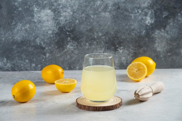 Une tasse en verre de jus de citron frais sur une planche de bois.