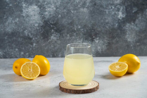 Une tasse en verre de jus de citron frais sur une planche de bois.