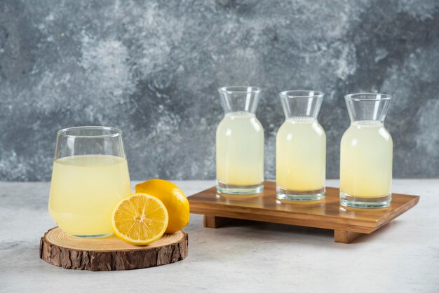 Une tasse en verre de jus de citron frais sur une planche de bois.