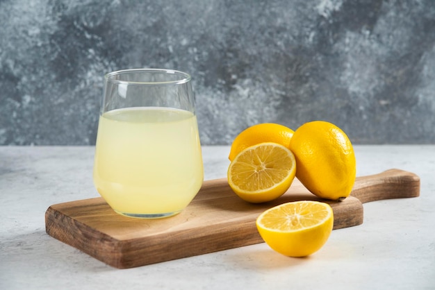 Une tasse en verre de jus de citron frais sur une planche de bois.